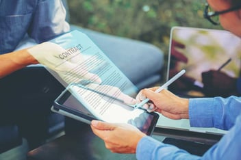 Person using a stylus to electronically sign a digital agreement on a tablet.